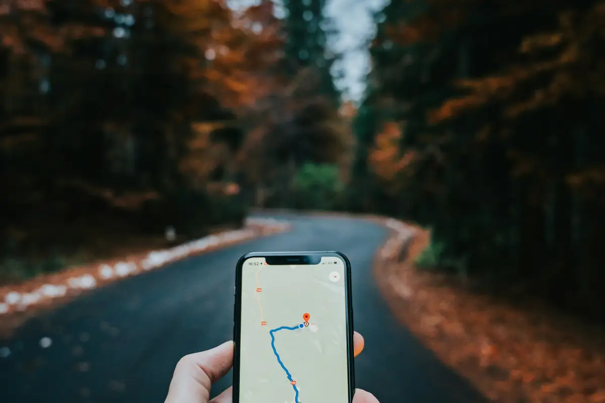 A hand holding a smartphone that shows a map with a route